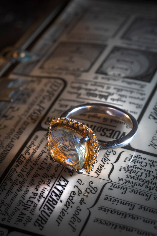 Bague en Argent 925 mm, centrée d’un quartz en briolette entouré de petits saphirs jaunes.